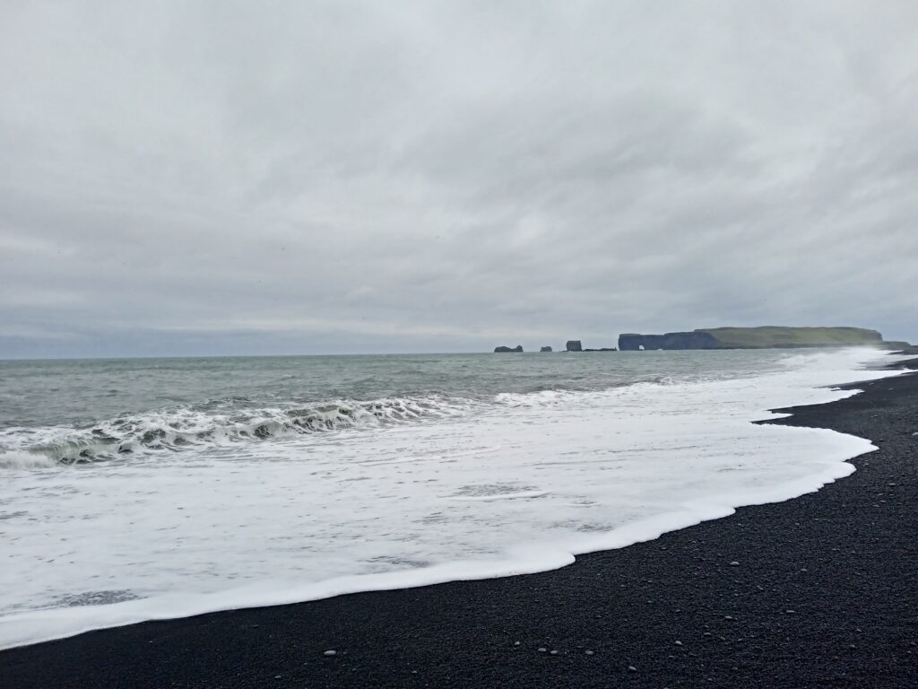Czarna plaża Reynisfjara sprzed jej erozji – fale z cyplem Dyrhólaey w tle